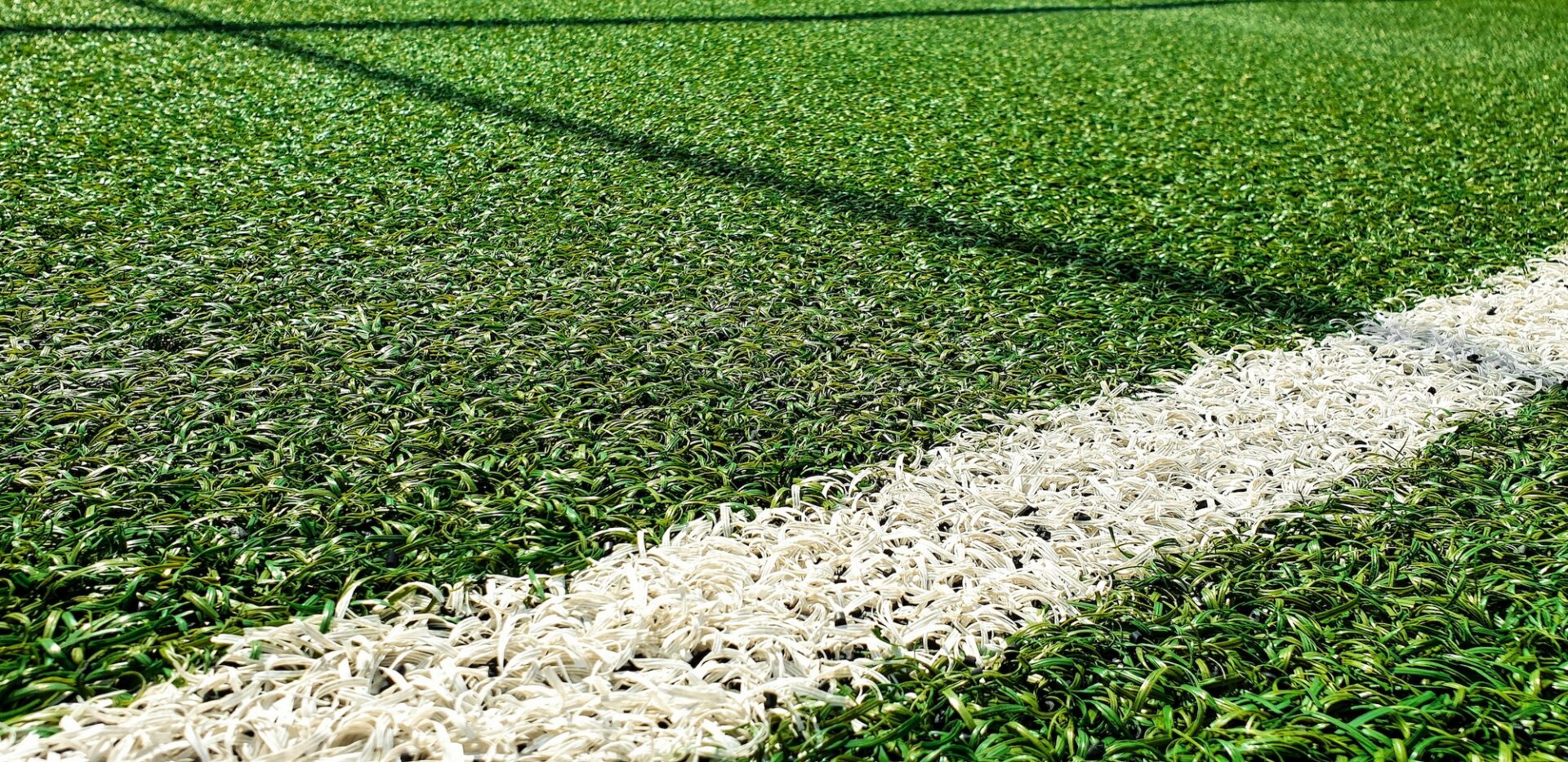 Close-up image of white line on artificial green football turf.
