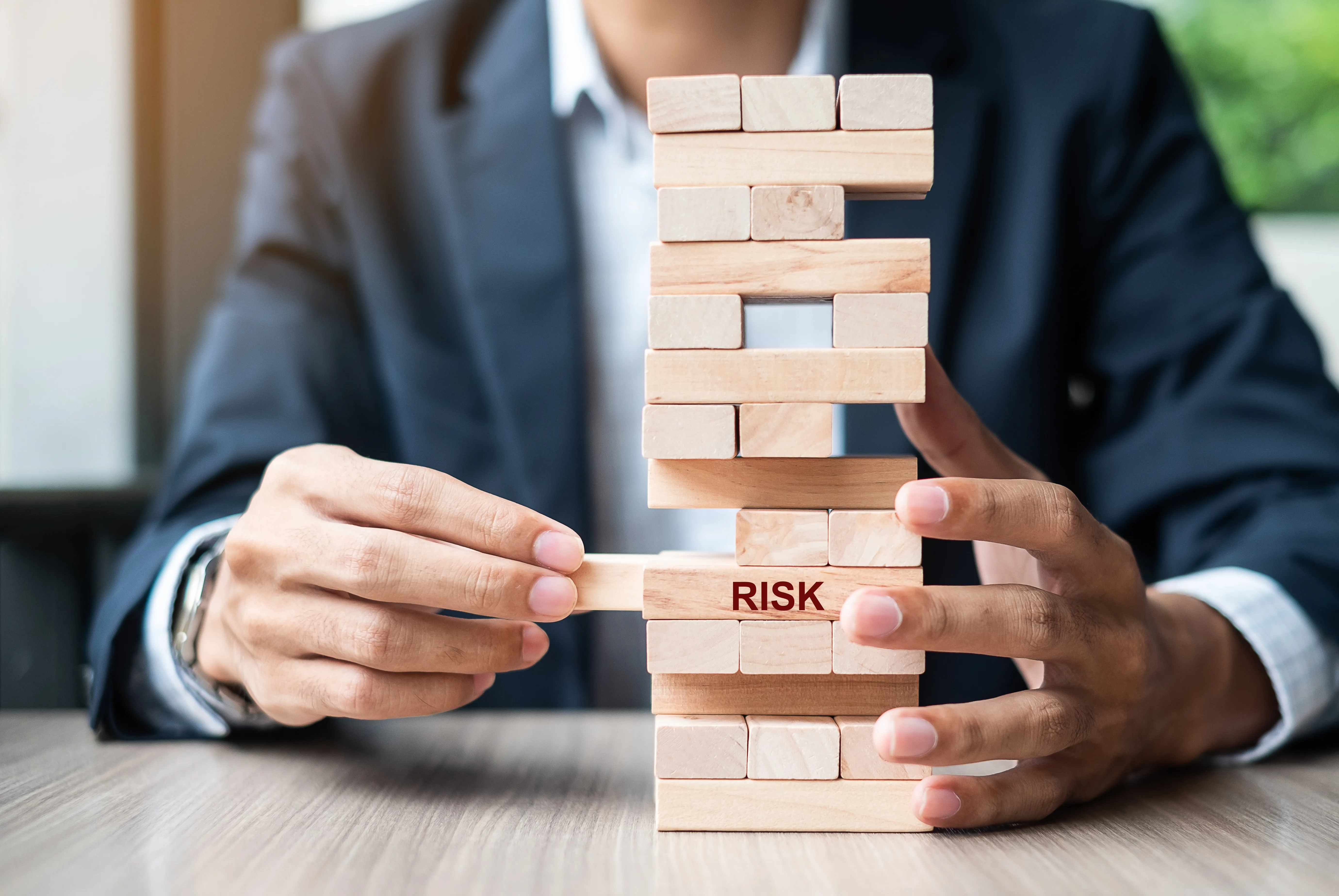 Businessman hand placing or pulling wooden block on the tower. Business planning, Risk Management,