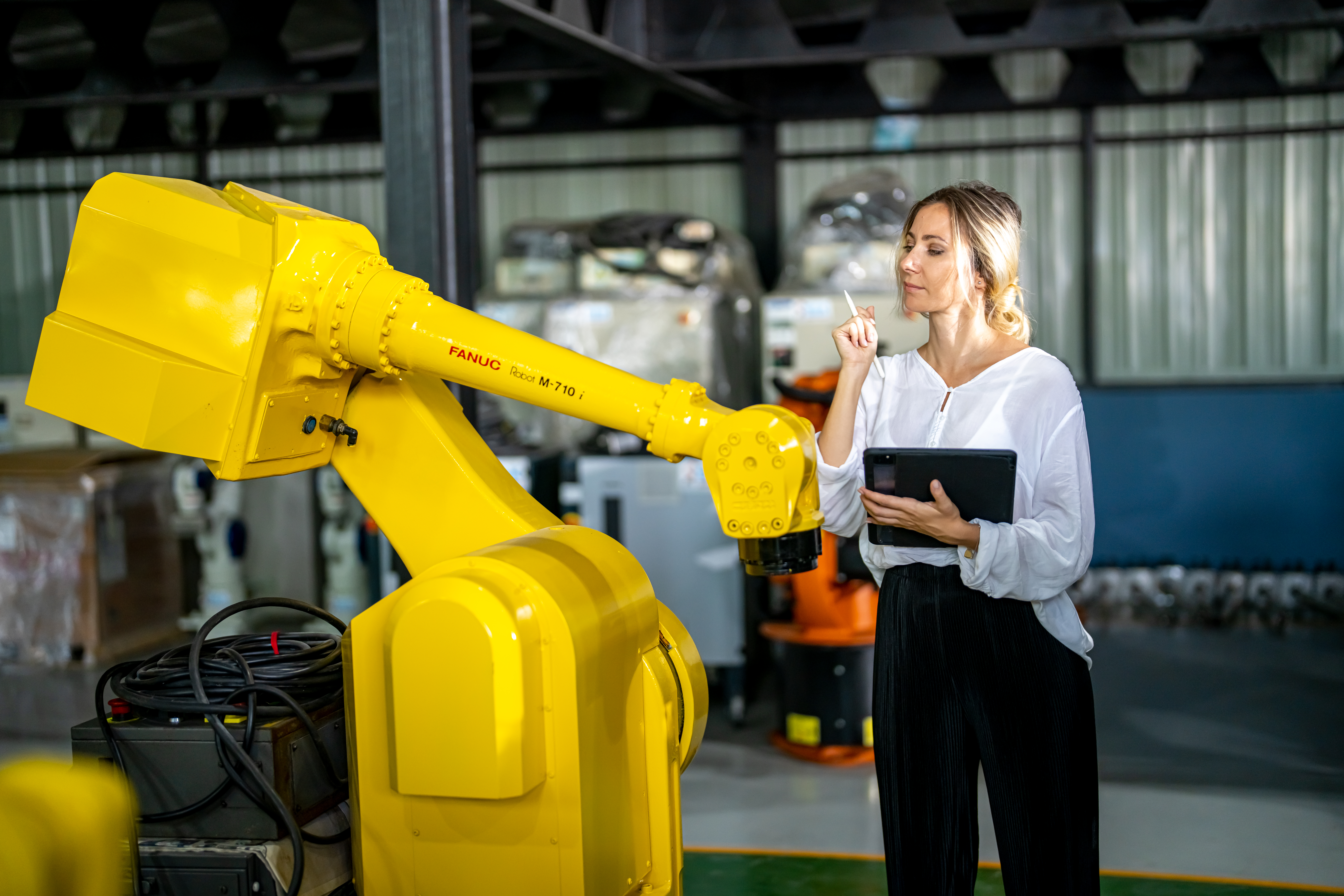 Engineer inspecting automatic AI robot arm and machines in factory. Engineer inspecting automatic AI