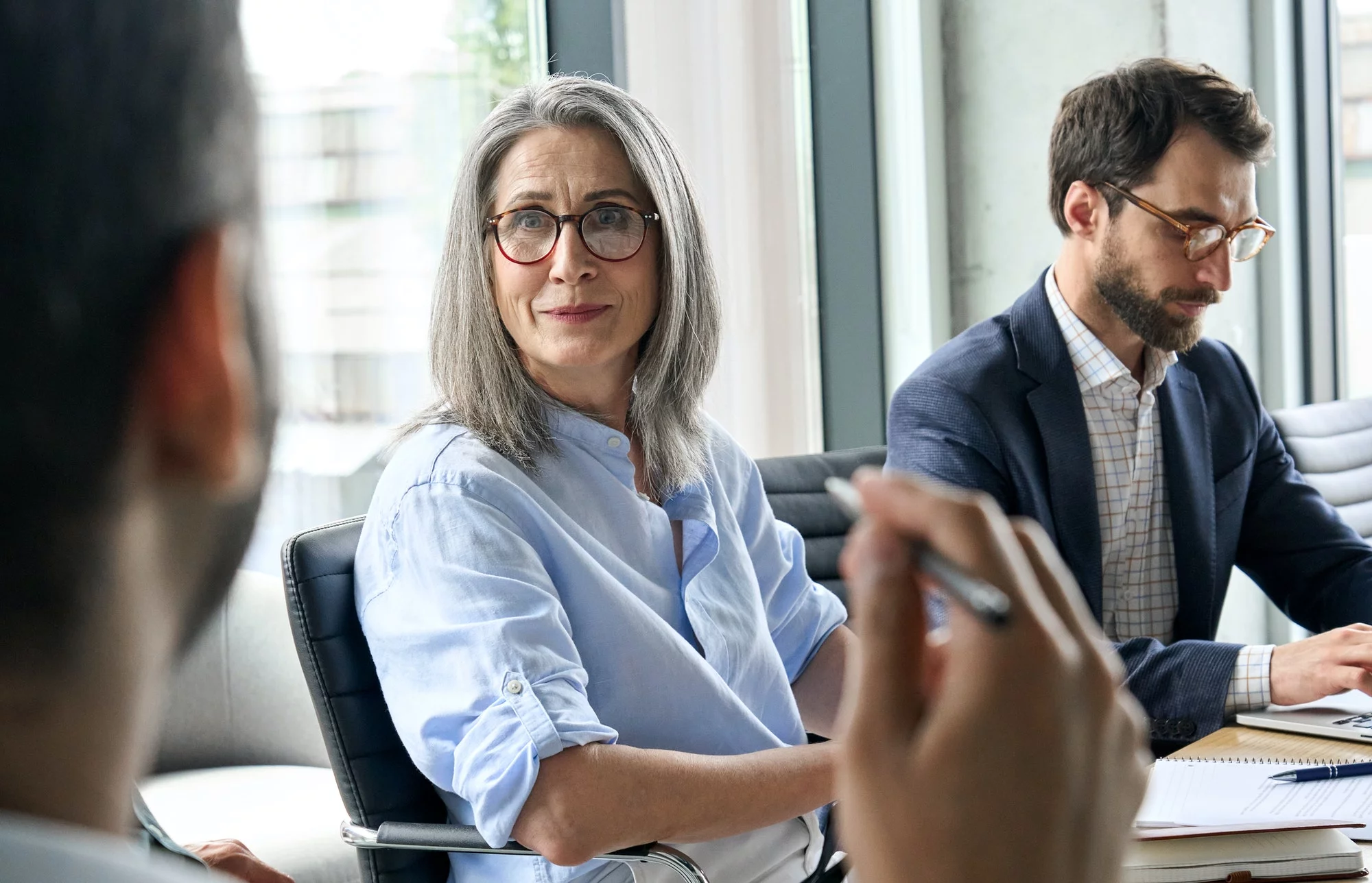 Smiling female ceo looking at male manager colleague at table meeting.