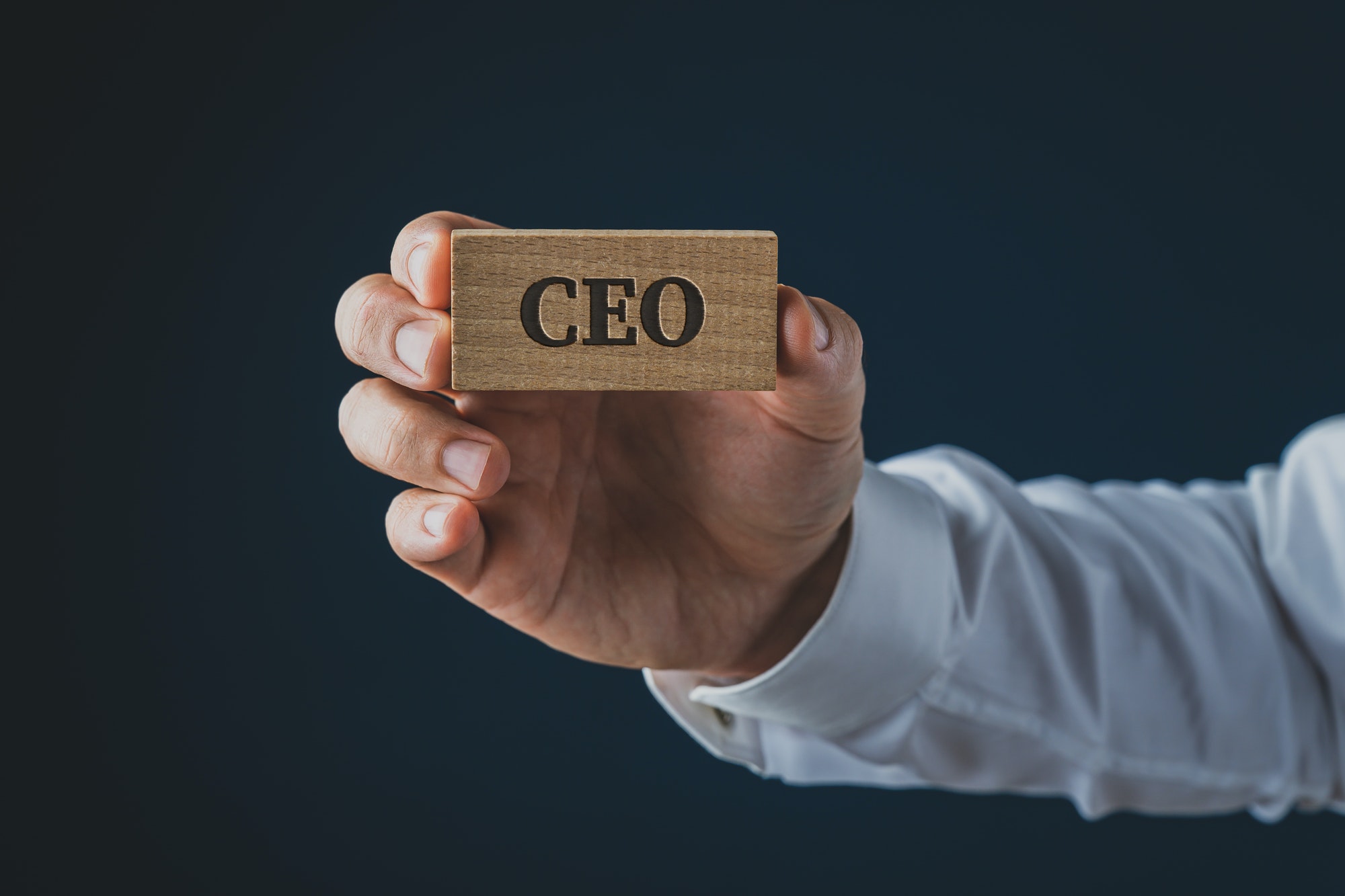Businessman showing a wooden identity card with the word CEO on it
