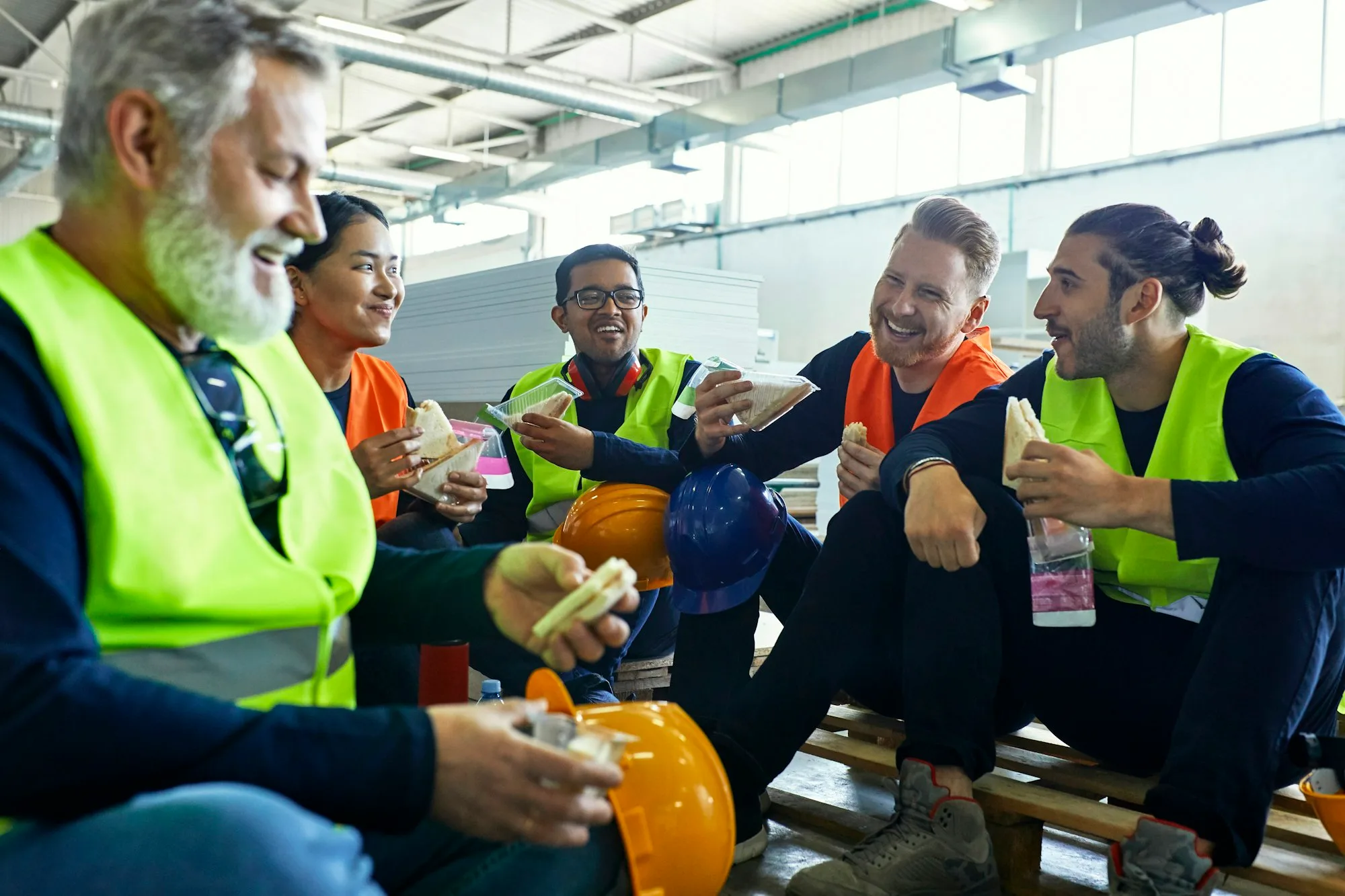 Happy workers in factory having lunch break together