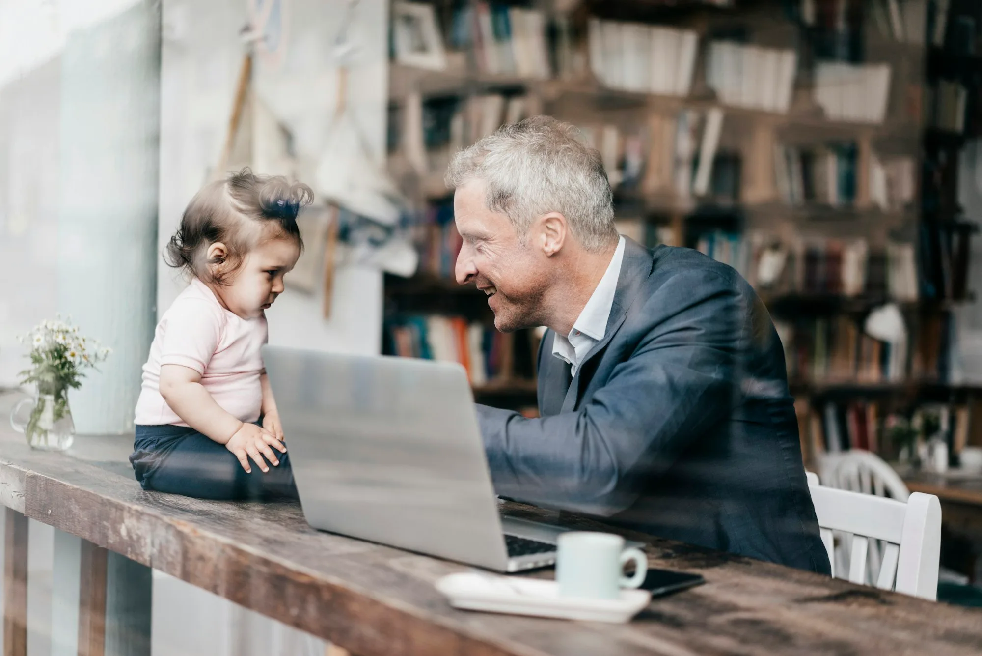 Businessman with little daughter working on laptop in cafe